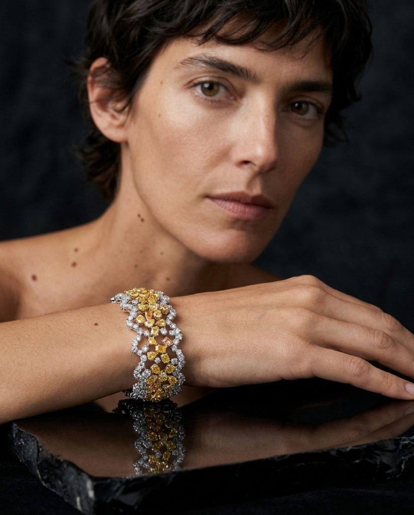 Woman wearing a yellow and white diamond cuff bracelet on dark marble